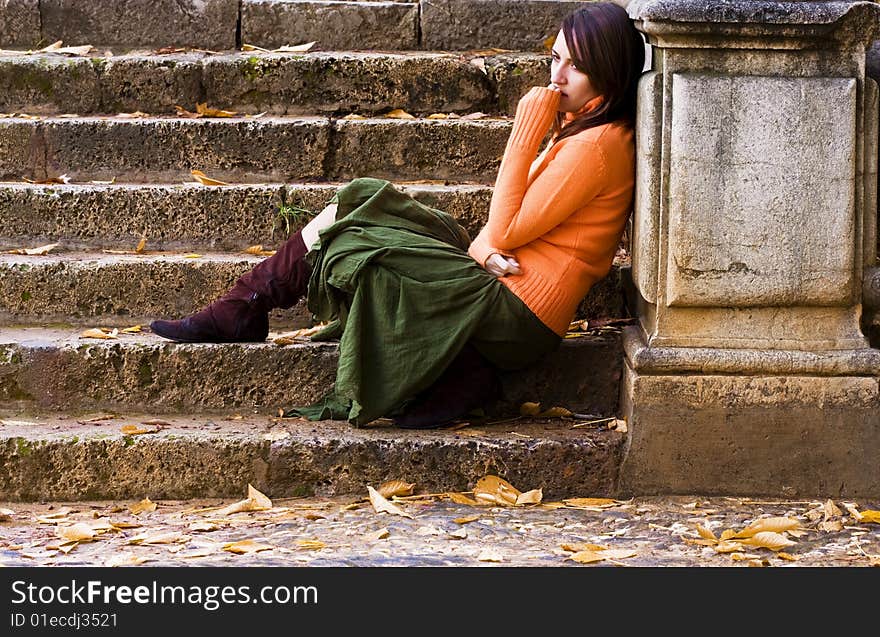 Young thoughtful woman sitting in stone stairs.