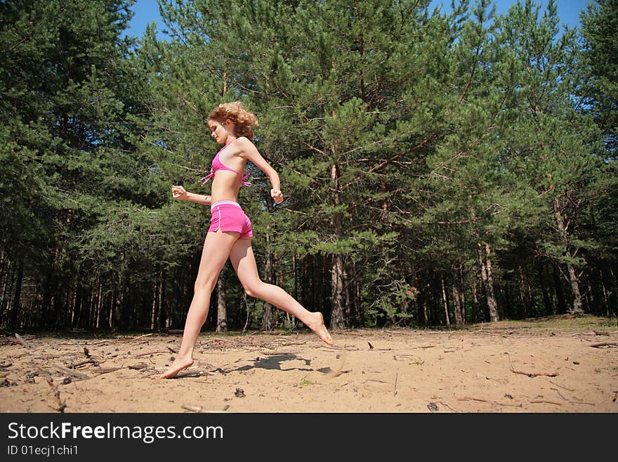 Young girl runs on sand in wood. Young girl runs on sand in wood