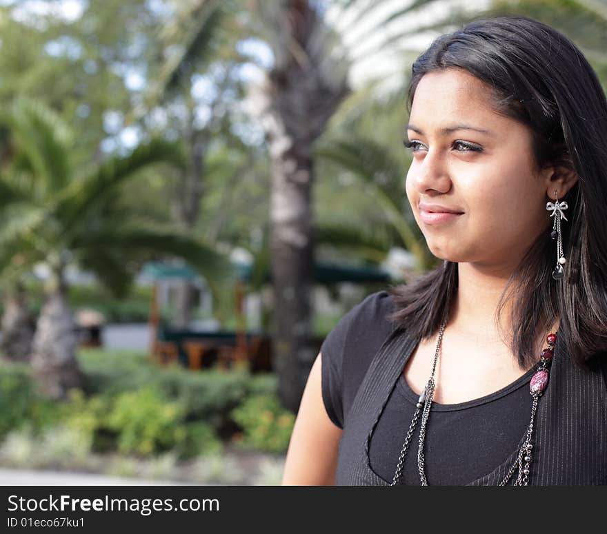 Young woman outside smiling and looking away from the camera. Young woman outside smiling and looking away from the camera