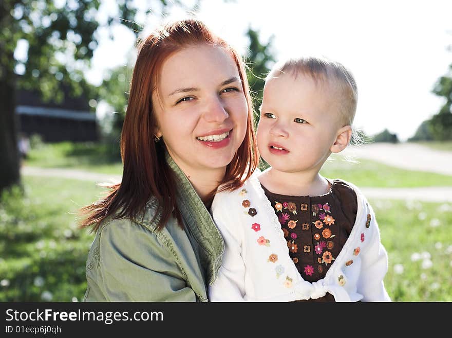 Portrait of a young tender mother with her little daughter during their walk in park in sunny summer day. Portrait of a young tender mother with her little daughter during their walk in park in sunny summer day