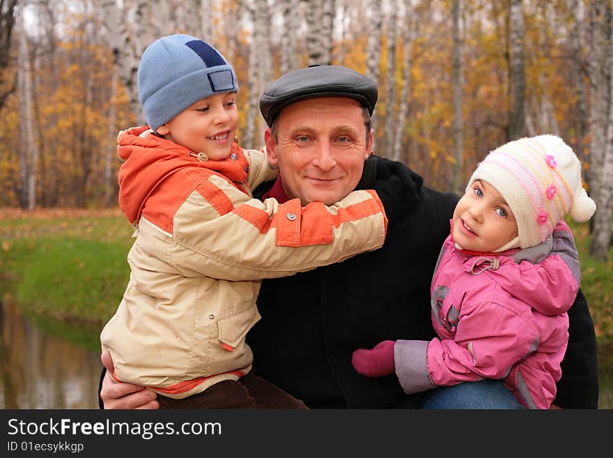 Grandfather with two children in autumnal park