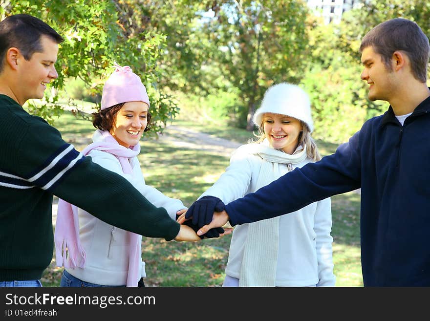 Four young male and female friends join hands in park environment. concept for unity. Four young male and female friends join hands in park environment. concept for unity