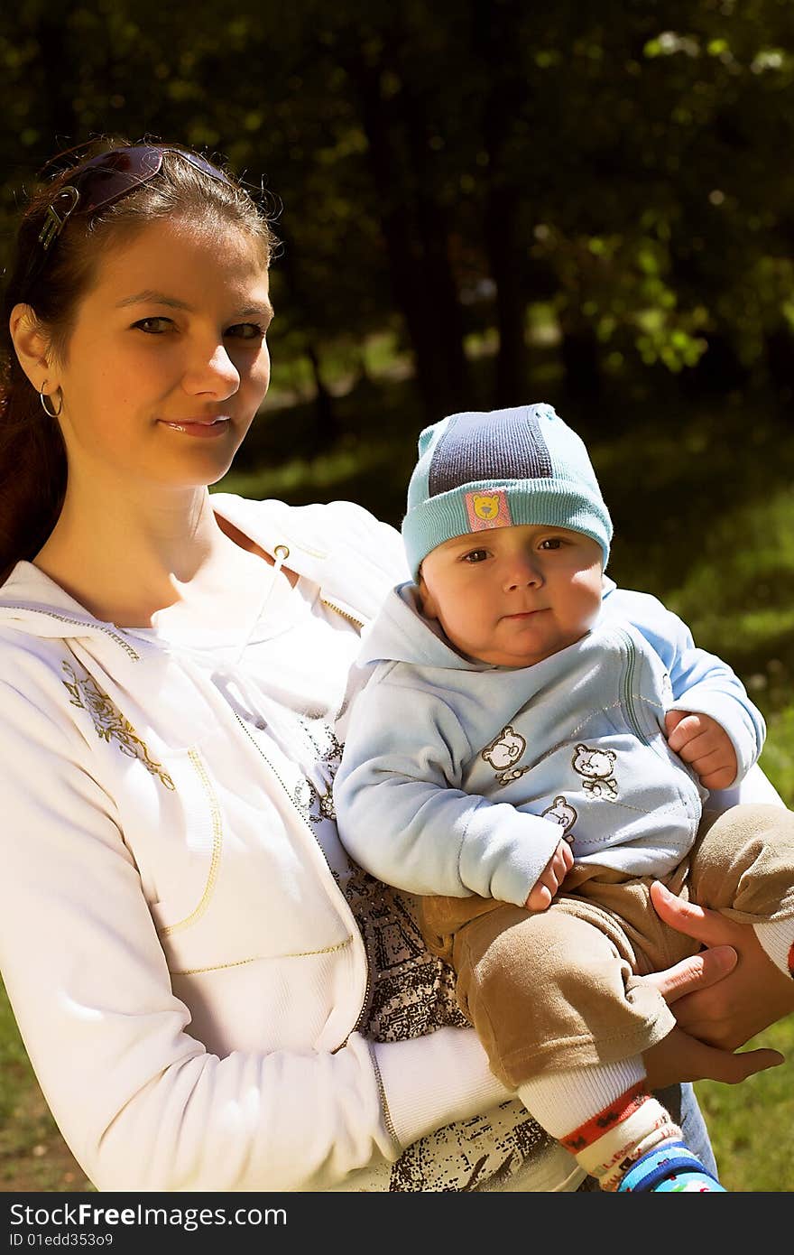 Portrait of a young beautiful mother holding her child, taken in park in sunny summer day. Portrait of a young beautiful mother holding her child, taken in park in sunny summer day