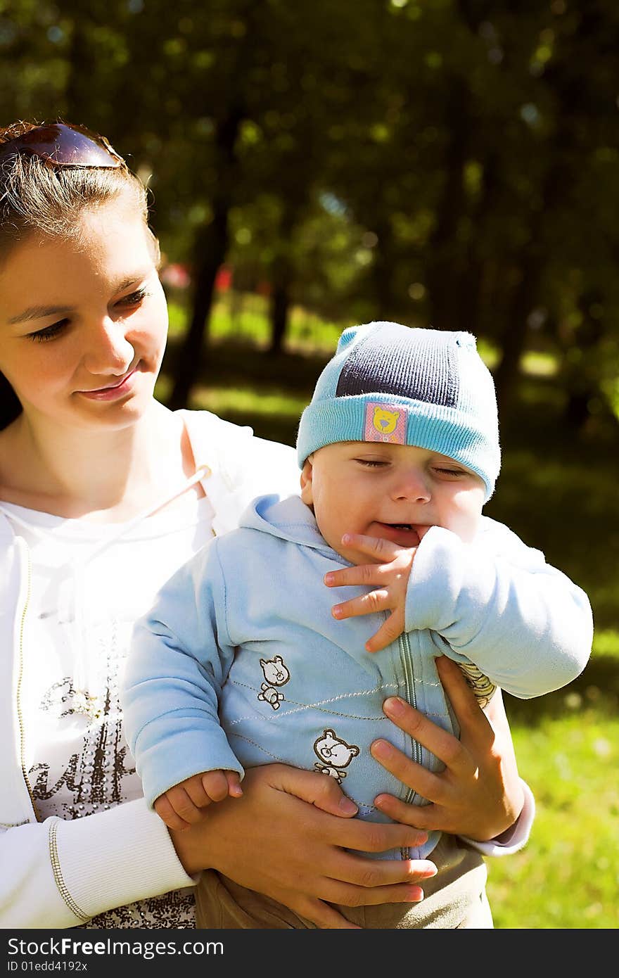 Portrait of a young beautiful mother holding her child, taken in park in sunny summer day. Portrait of a young beautiful mother holding her child, taken in park in sunny summer day