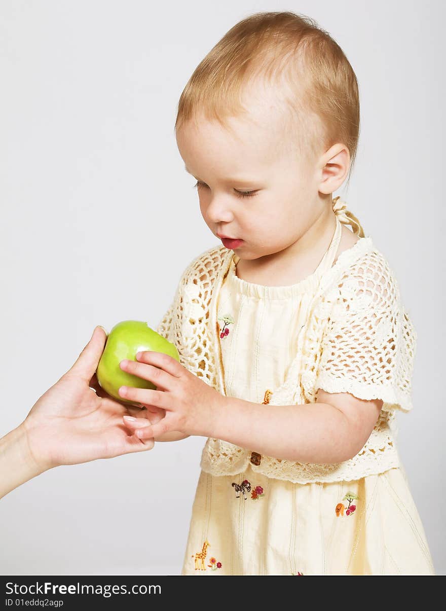 Studio portrait of a little girl taking an apple from the mother's hand. Studio portrait of a little girl taking an apple from the mother's hand