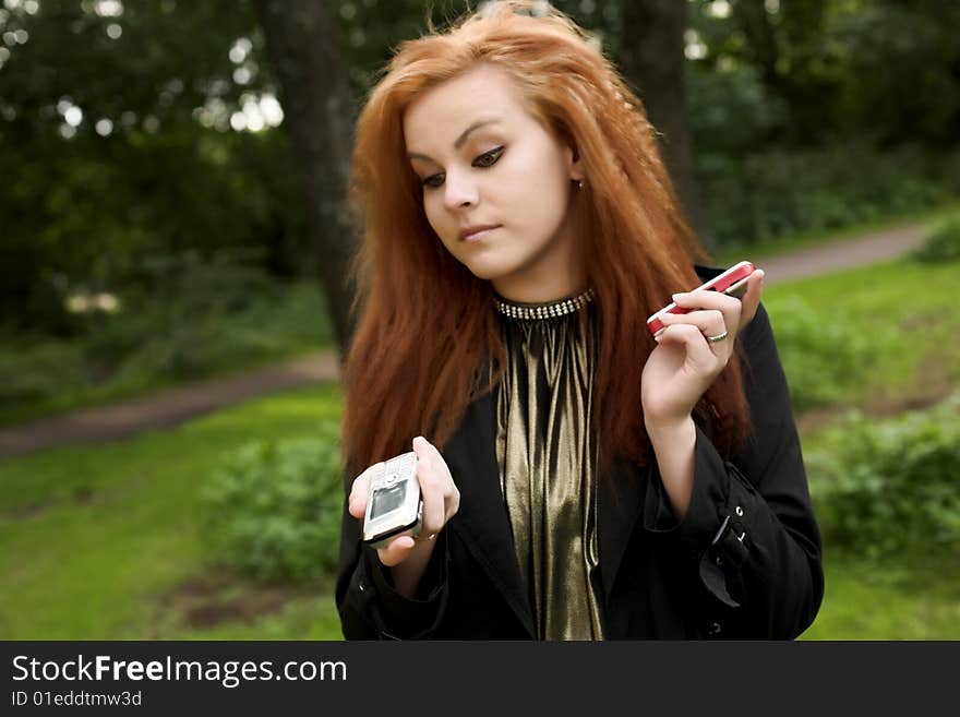 Young attractive girl talking on a phone while strolling in the park. Young attractive girl talking on a phone while strolling in the park.