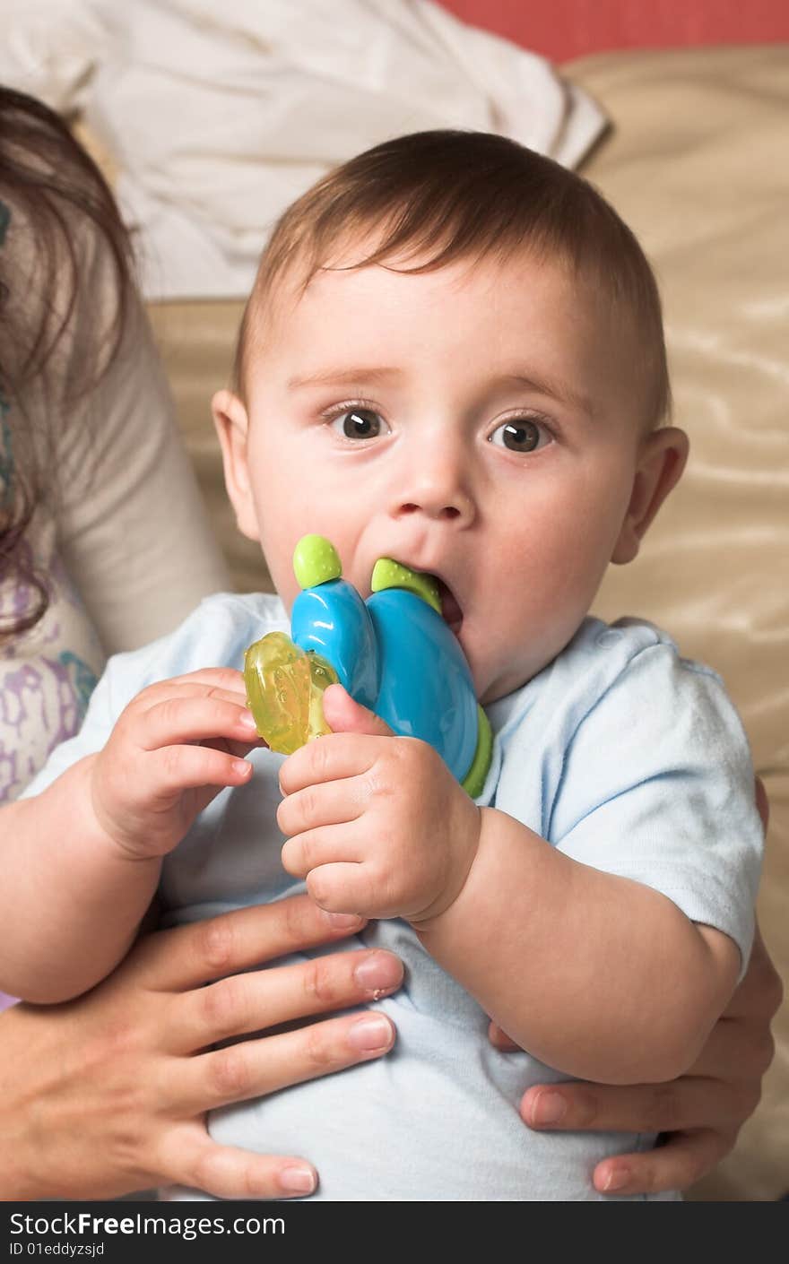 Little child carrying by his mother and nibbling a toy. Little child carrying by his mother and nibbling a toy