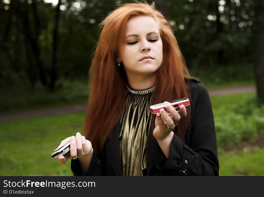 Young attractive girl talking on a phone while strolling in the park. Young attractive girl talking on a phone while strolling in the park.