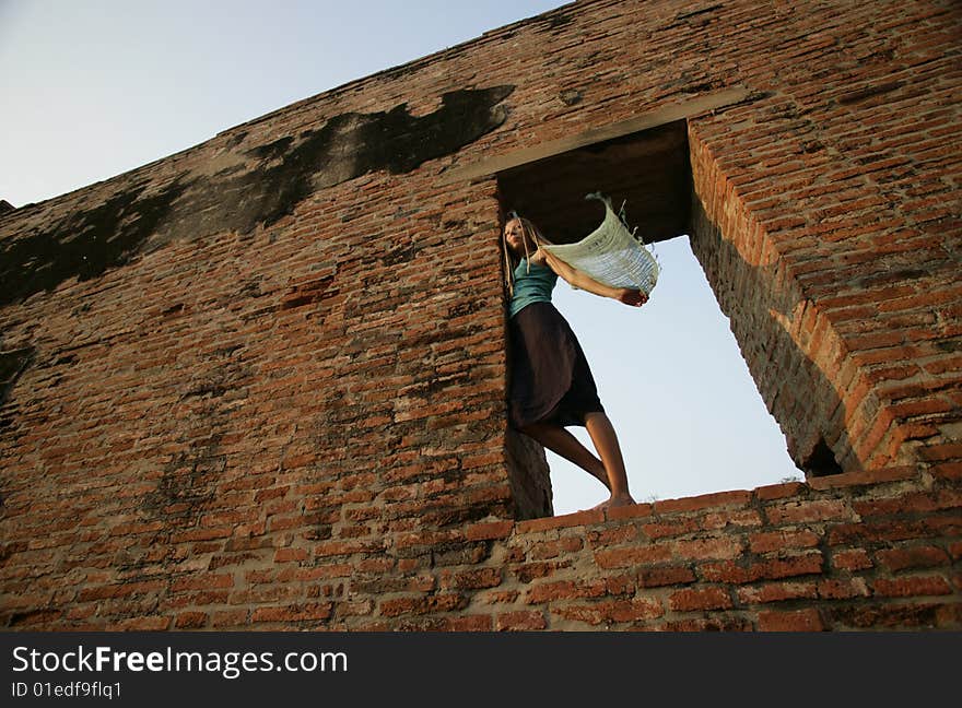 A girl with streaming blue scarf in the window opening. A girl with streaming blue scarf in the window opening