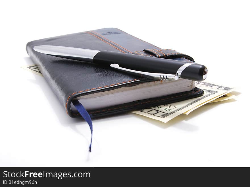 Leather notebook and pen lying on american dollars isolated on white