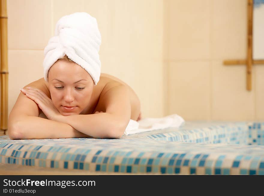 The girl in a towel lies on the brink of pool. The girl in a towel lies on the brink of pool