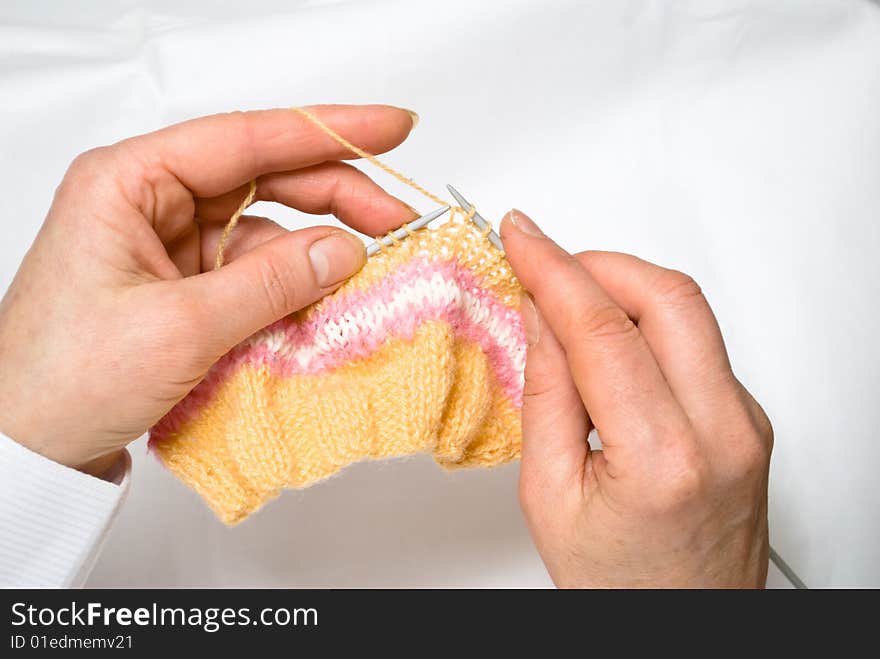 Two hands knitting a wool dress