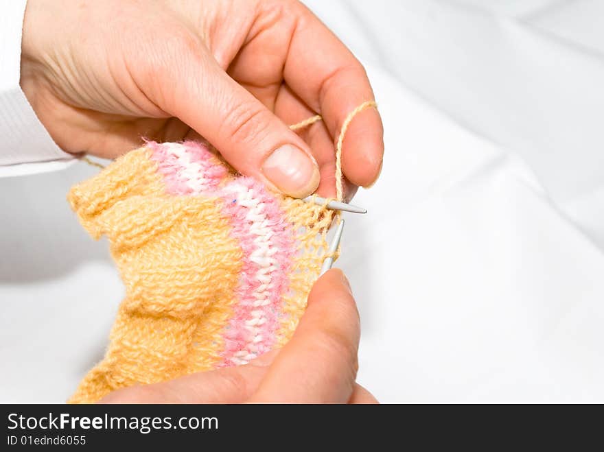 Two hands knitting a wool dress