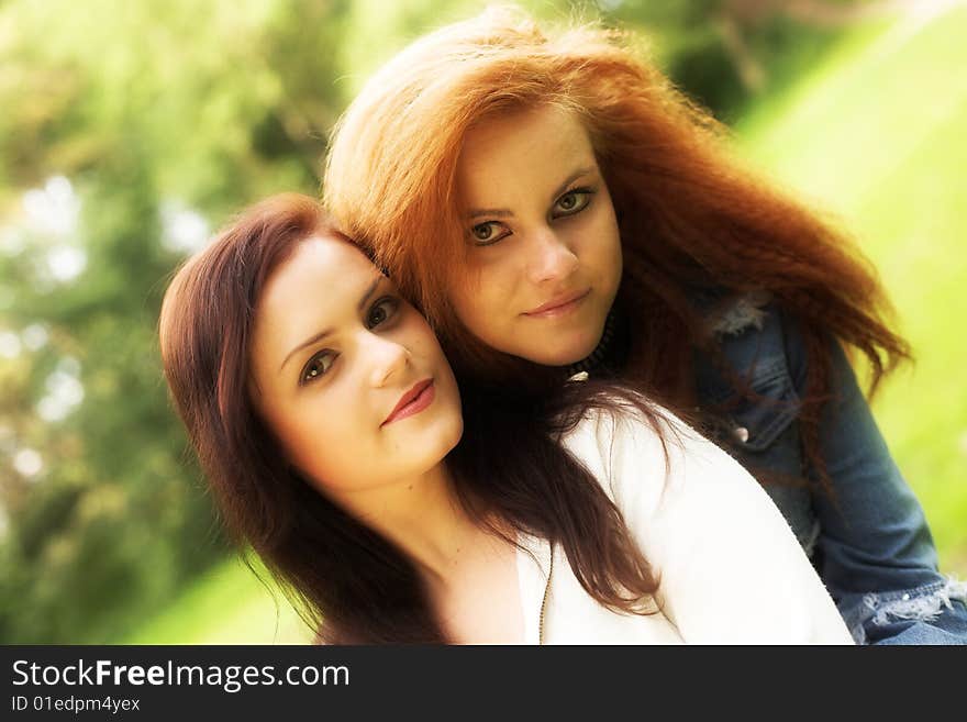 Close-up portrait of two girl-friends during their walk in a park. Close-up portrait of two girl-friends during their walk in a park