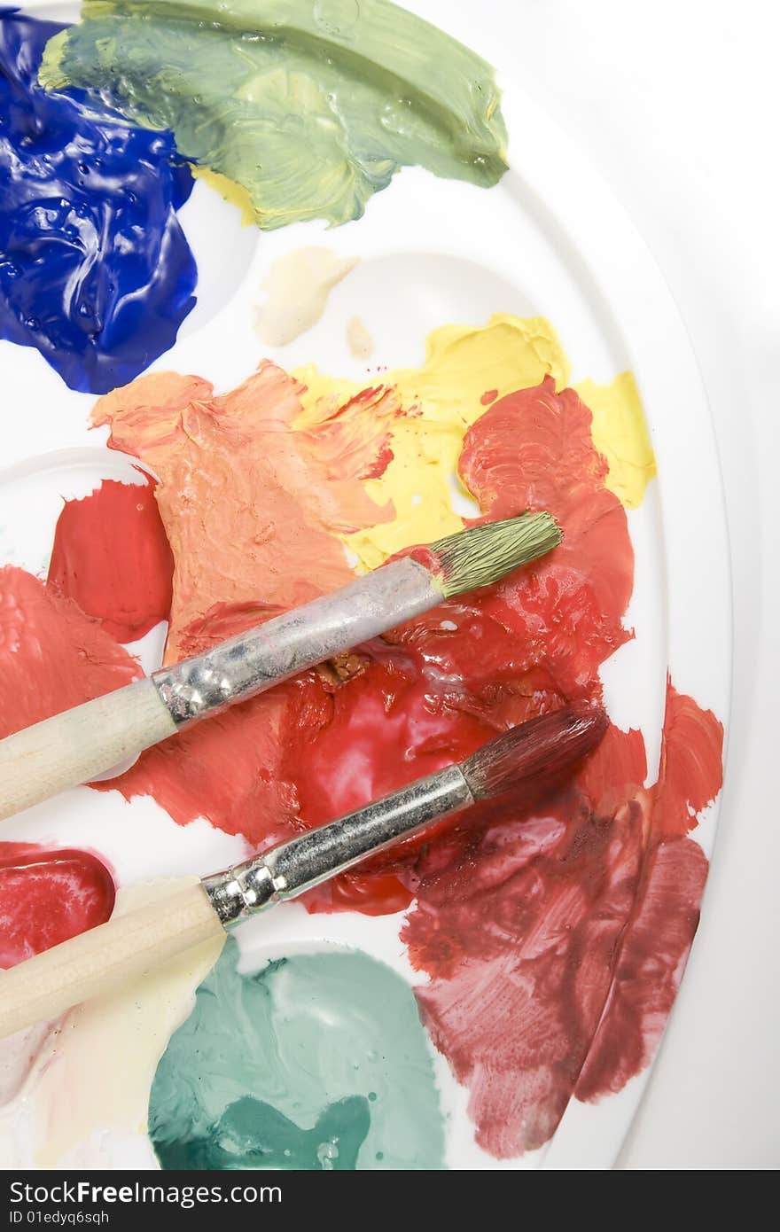 White palette with mixed paints and paintbrushes. White palette with mixed paints and paintbrushes