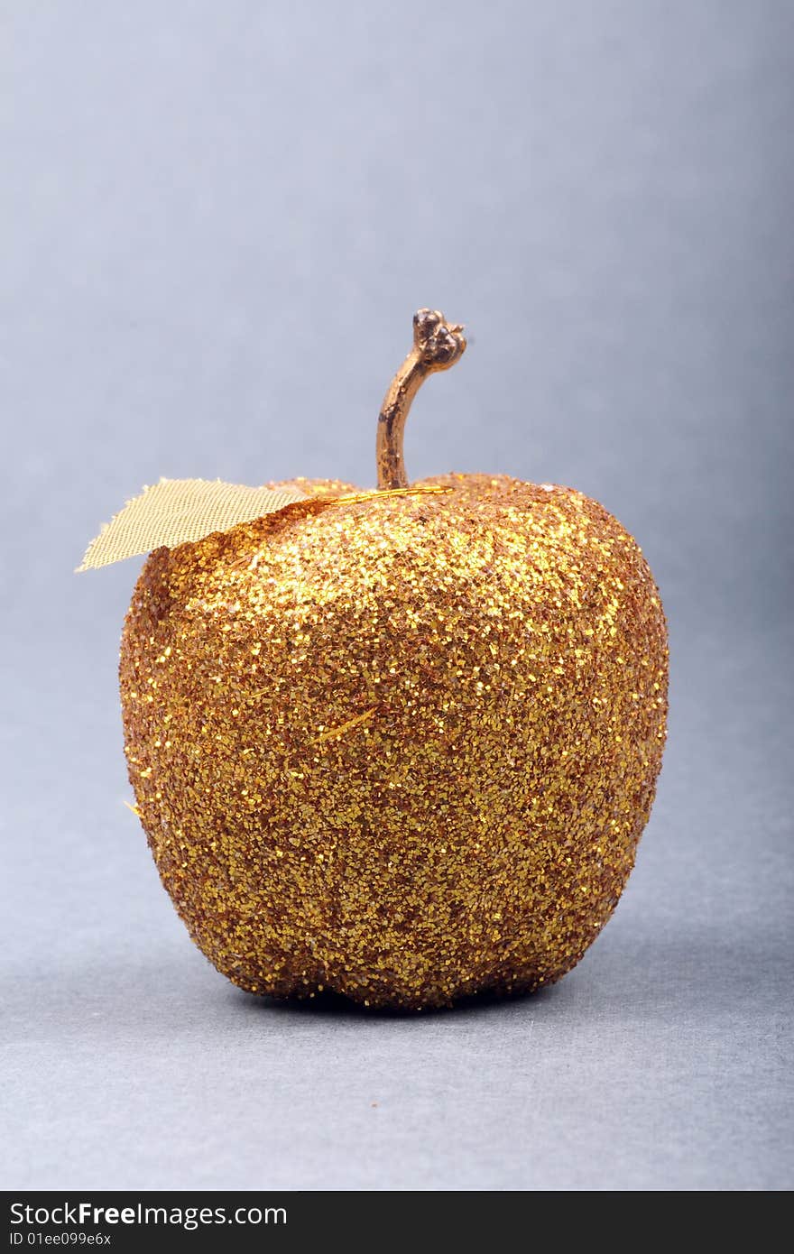 A golden apple is on gray background