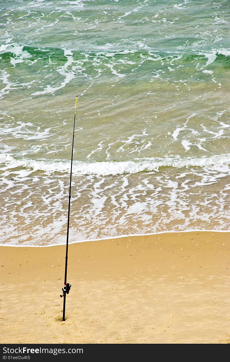 Fishing-rod fixed in the sand.  Expecting for a big catch fish. Fishing-rod fixed in the sand.  Expecting for a big catch fish.