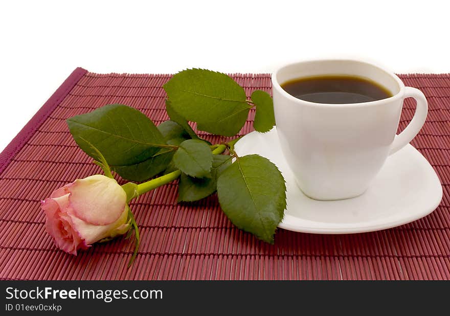 White cup of coffee and rose which lies on a table