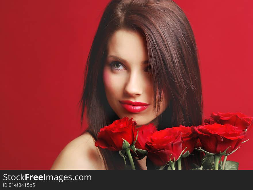 Close-up studio portrait of a beautiful woman with red rose, shoot on red background