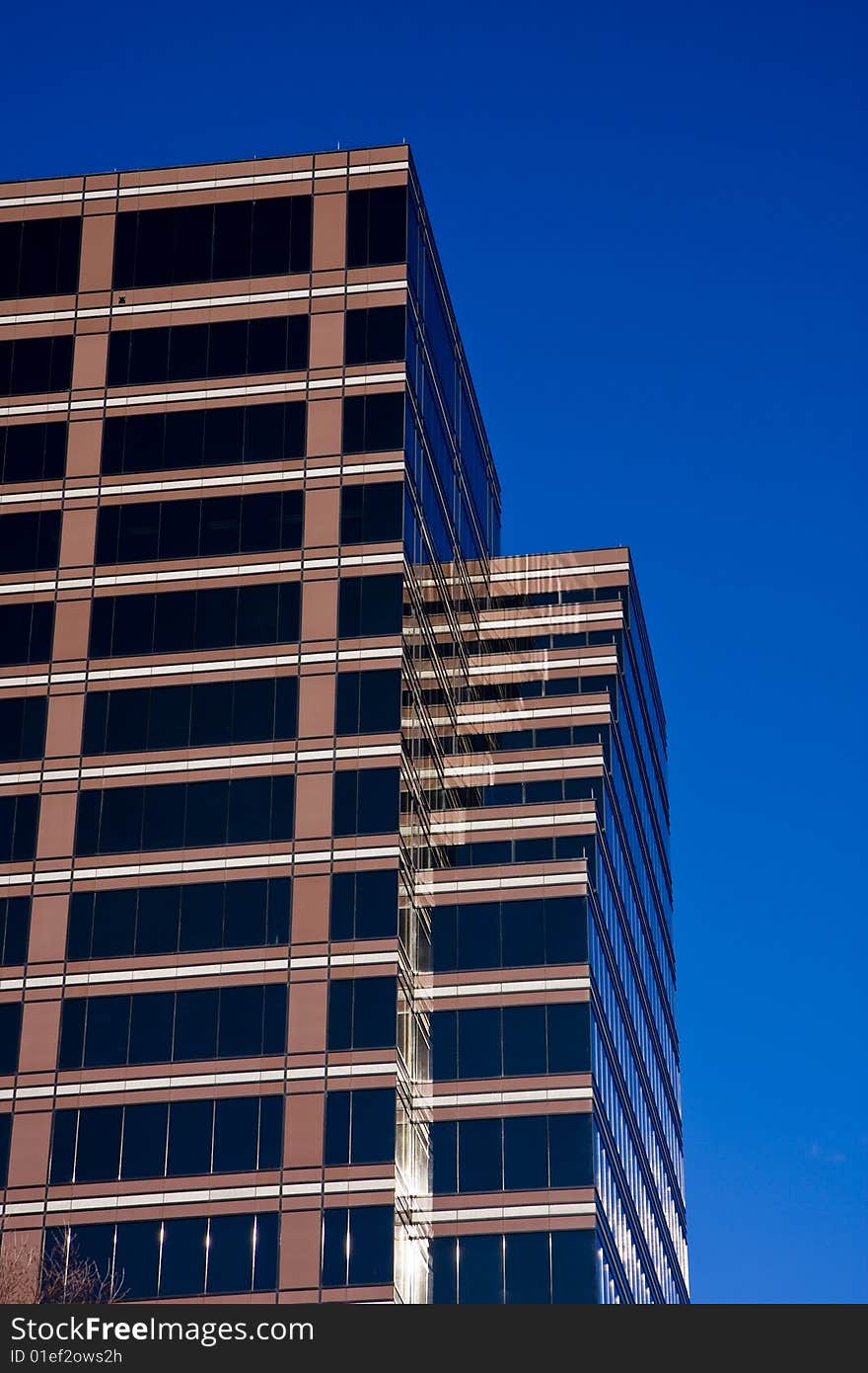 A modern brown glass office building against blue sky. A modern brown glass office building against blue sky