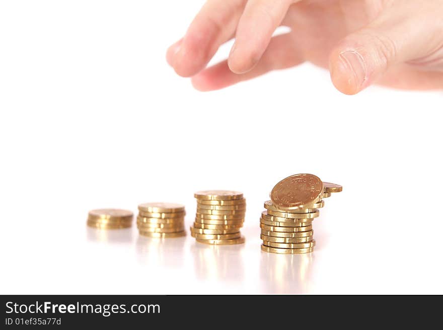 A hand is stacking up coins. The last coin dropped let's the tower tumble. Isolated over white. Ideal Businesshot. A hand is stacking up coins. The last coin dropped let's the tower tumble. Isolated over white. Ideal Businesshot.