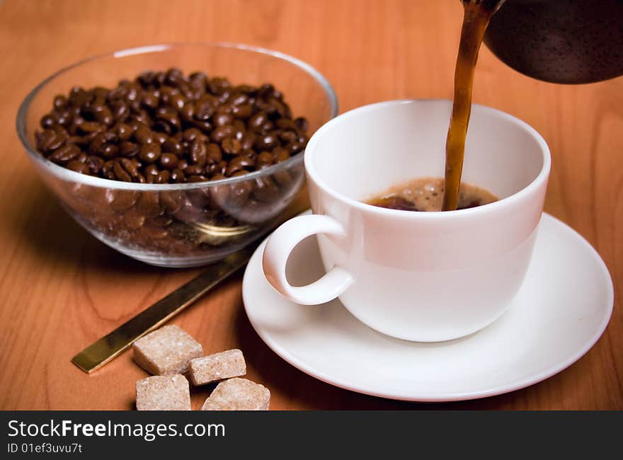 Cup of coffee, sugar and beans in glass bowl on wooden table