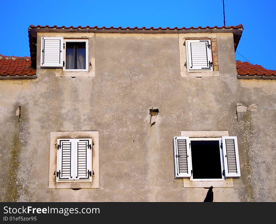 Wall with four windows two of wich is open & blue sky