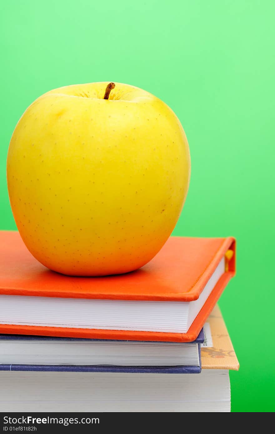 Yellow apple on stack of books against green background. Yellow apple on stack of books against green background.