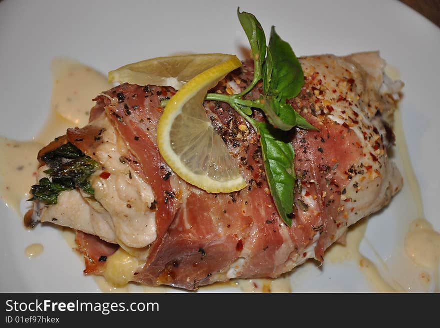 Chicken roll filled with asparagus spears, wrapped in prosciutto, topped with fresh lemon and basil.