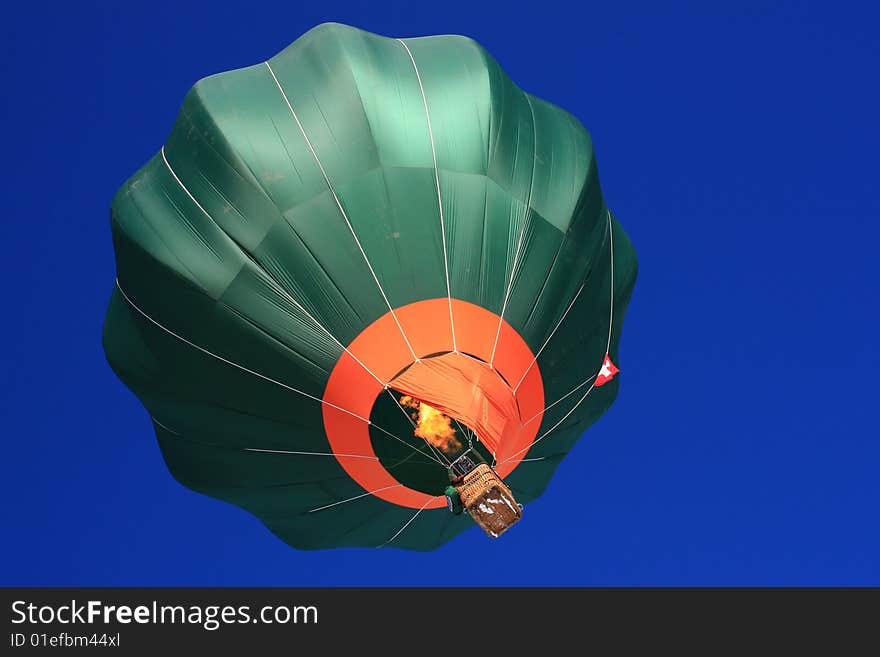 Dark green balloon designed for fast manuvering taking off from the launch side of Chateau d'Oex International Festival of Hot-Air Balloons 2009. The heating flame is visible. Balloon registration numbers have been digitally removed. Dark green balloon designed for fast manuvering taking off from the launch side of Chateau d'Oex International Festival of Hot-Air Balloons 2009. The heating flame is visible. Balloon registration numbers have been digitally removed.