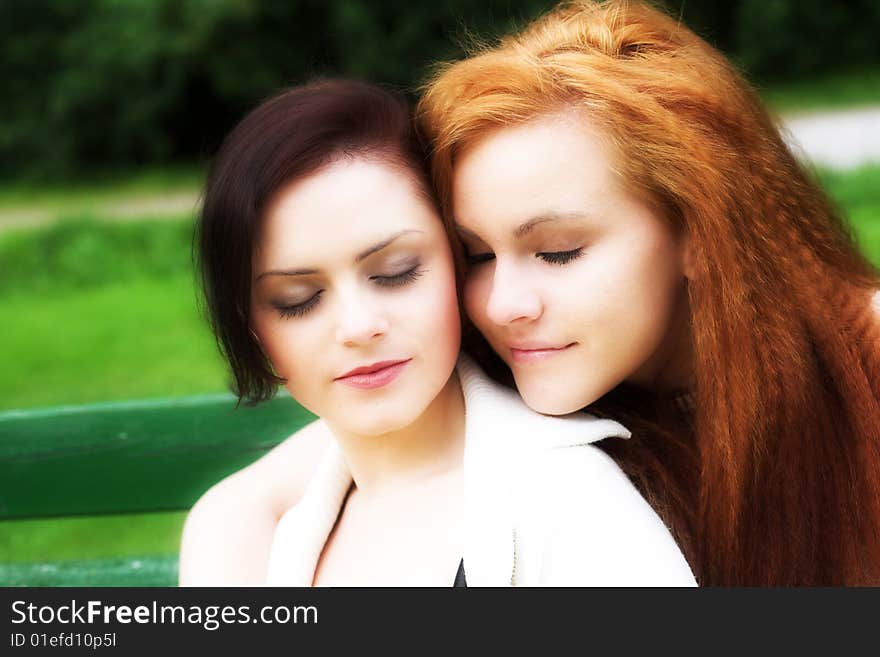 Close-up portrait of two girl-friends during their walk in a park. Close-up portrait of two girl-friends during their walk in a park