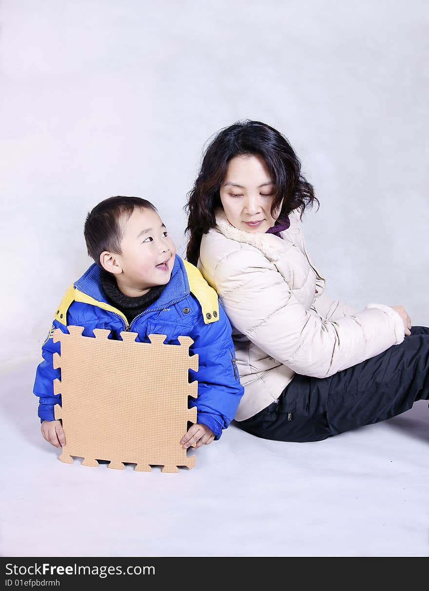 A laughing boy sitting on the floor looking at his mother. A laughing boy sitting on the floor looking at his mother.