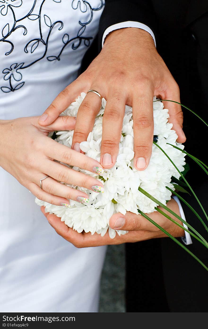 Hands of bride and groom on the bouquet. Hands of bride and groom on the bouquet