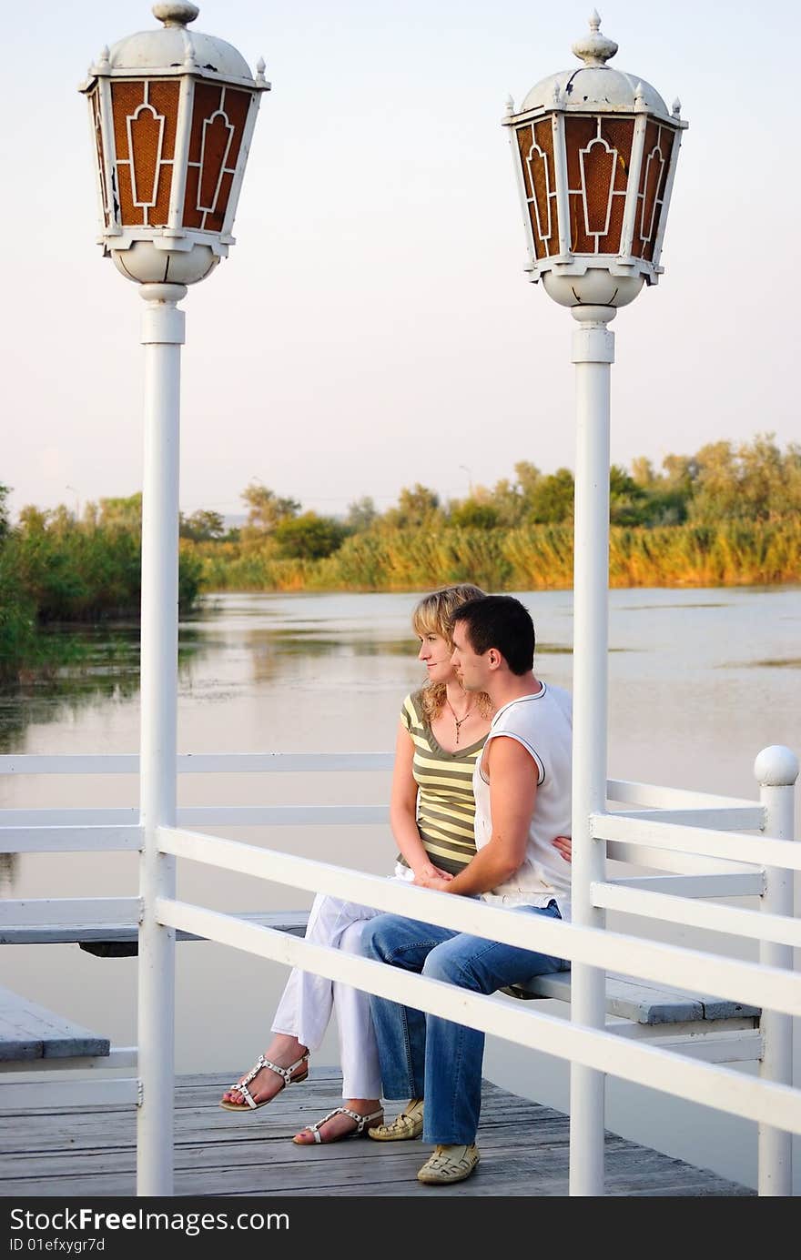 Pair on a pier. Look afar.