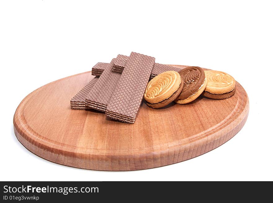 Wafers and cookie lie at the round board, isolated on a white background. Wafers and cookie lie at the round board, isolated on a white background.