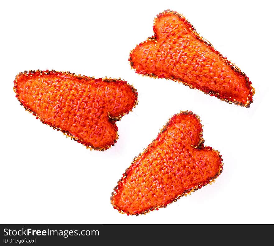 Three red hearts from a wool of manual work on a white background with an ornament. Three red hearts from a wool of manual work on a white background with an ornament