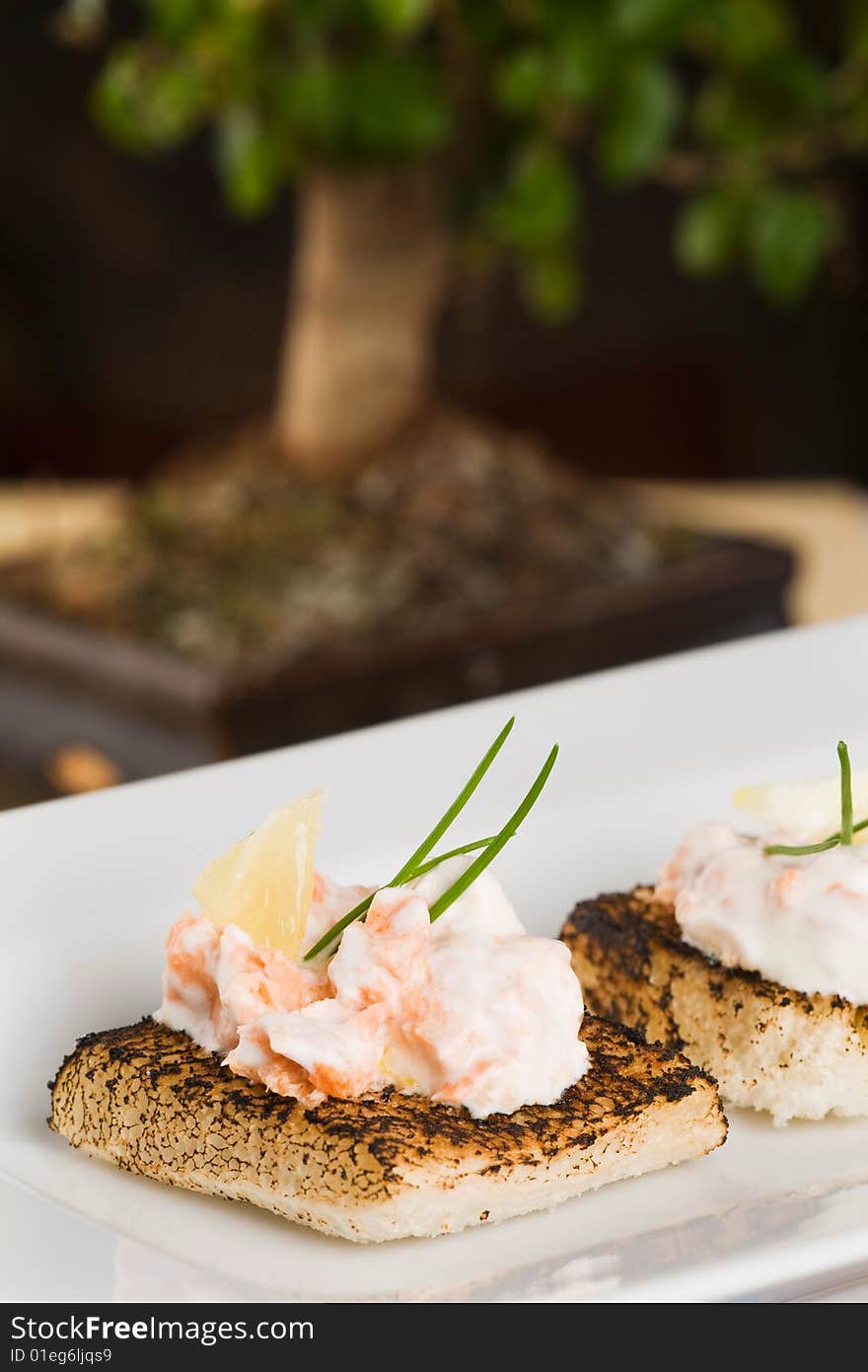 Salmon and creme fraiche toasts with chives to garnish. Salmon and creme fraiche toasts with chives to garnish