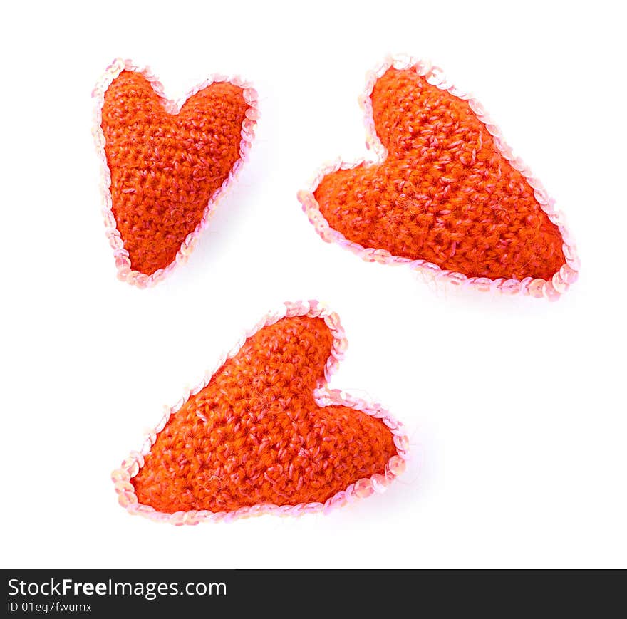 Three red hearts from a wool of manual work on a white background with an ornament. Three red hearts from a wool of manual work on a white background with an ornament