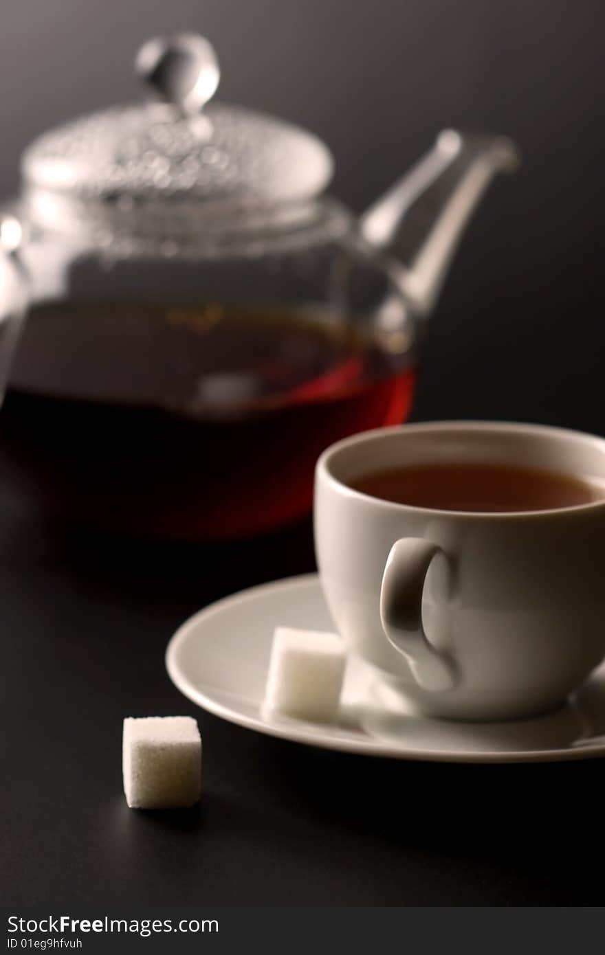 Cup of tea and tea pot over black