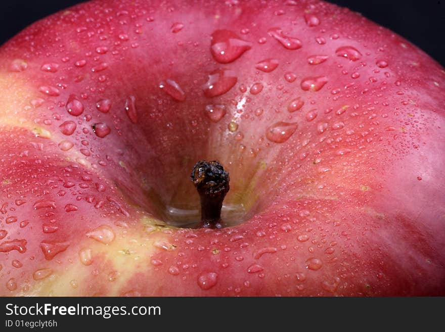 A close up of a red apple covered in dew.