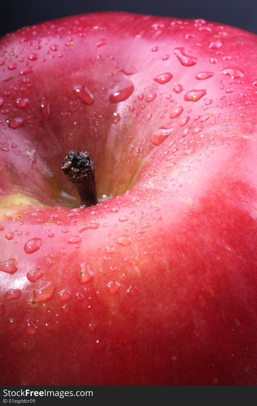 A close up of a red apple covered in dew.