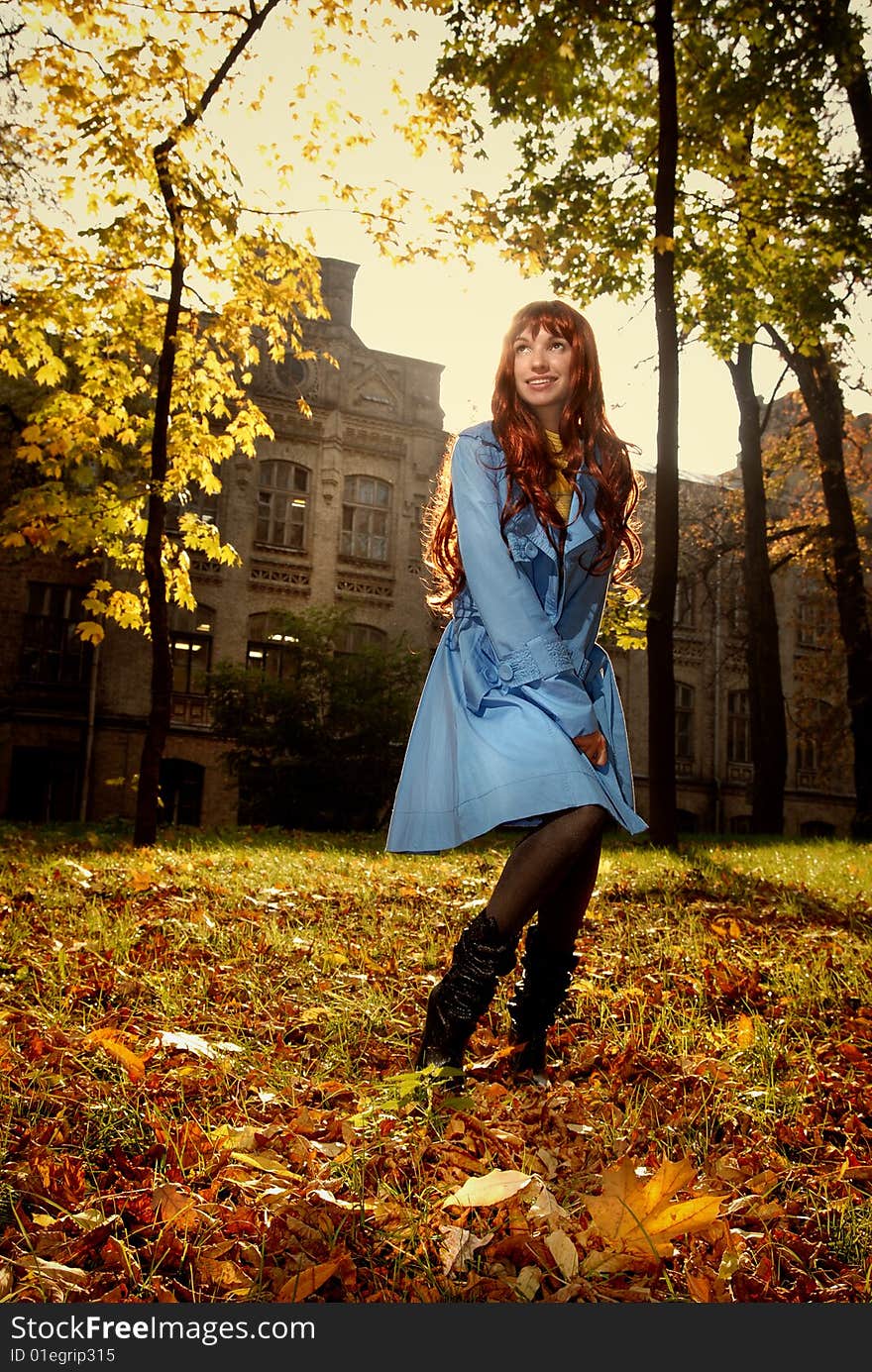 Woman in blue jaket posing in autumn park