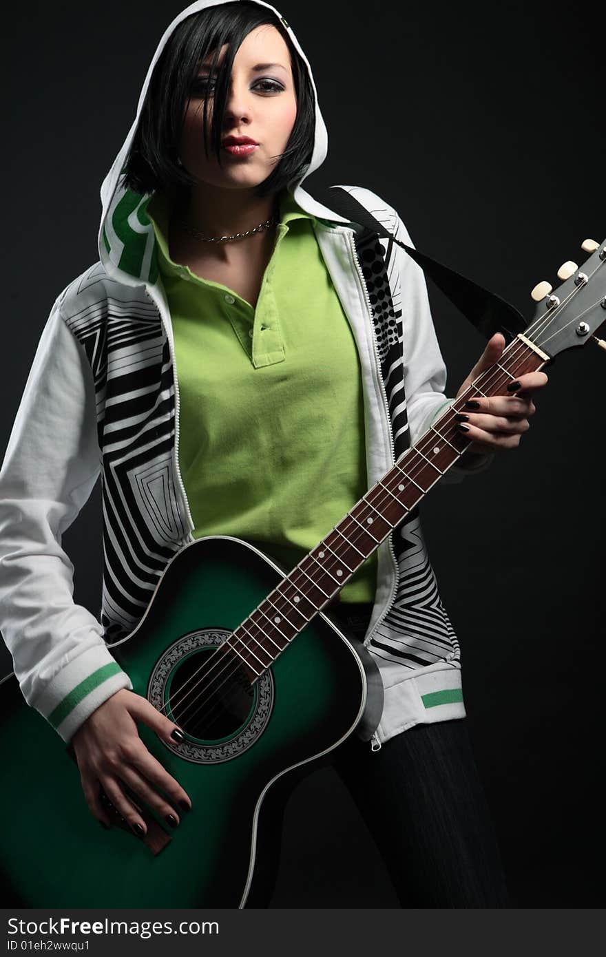Young emo girl with guitar on black background