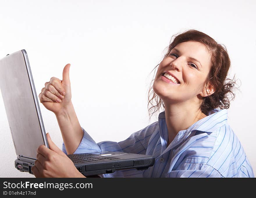 A young woman at home sitting on the floor with her laptop. She is very happy and gives a thumb up sign. A young woman at home sitting on the floor with her laptop. She is very happy and gives a thumb up sign.