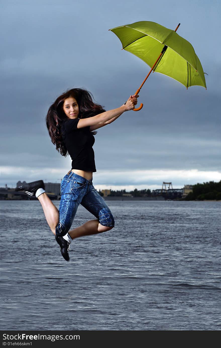 Girl jumping against sky and water with umbrella. Girl jumping against sky and water with umbrella