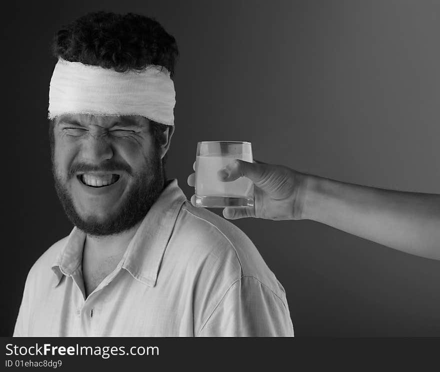 A man with a bandage on his head and a hand reaching in to offer water. . A man with a bandage on his head and a hand reaching in to offer water.