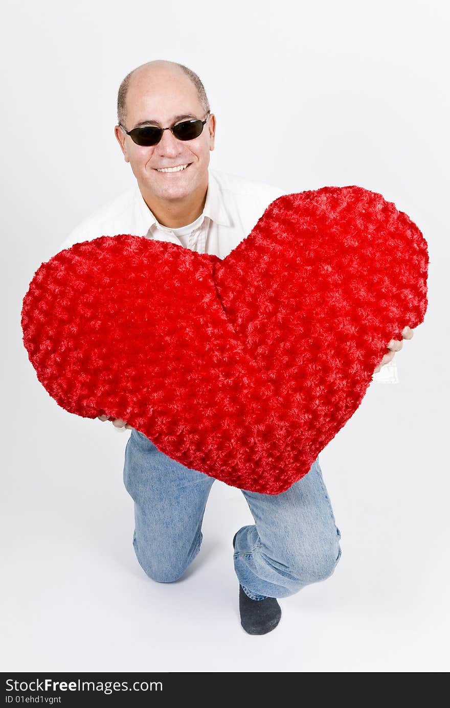 A handsome Latin man holding a big red heart. A handsome Latin man holding a big red heart.