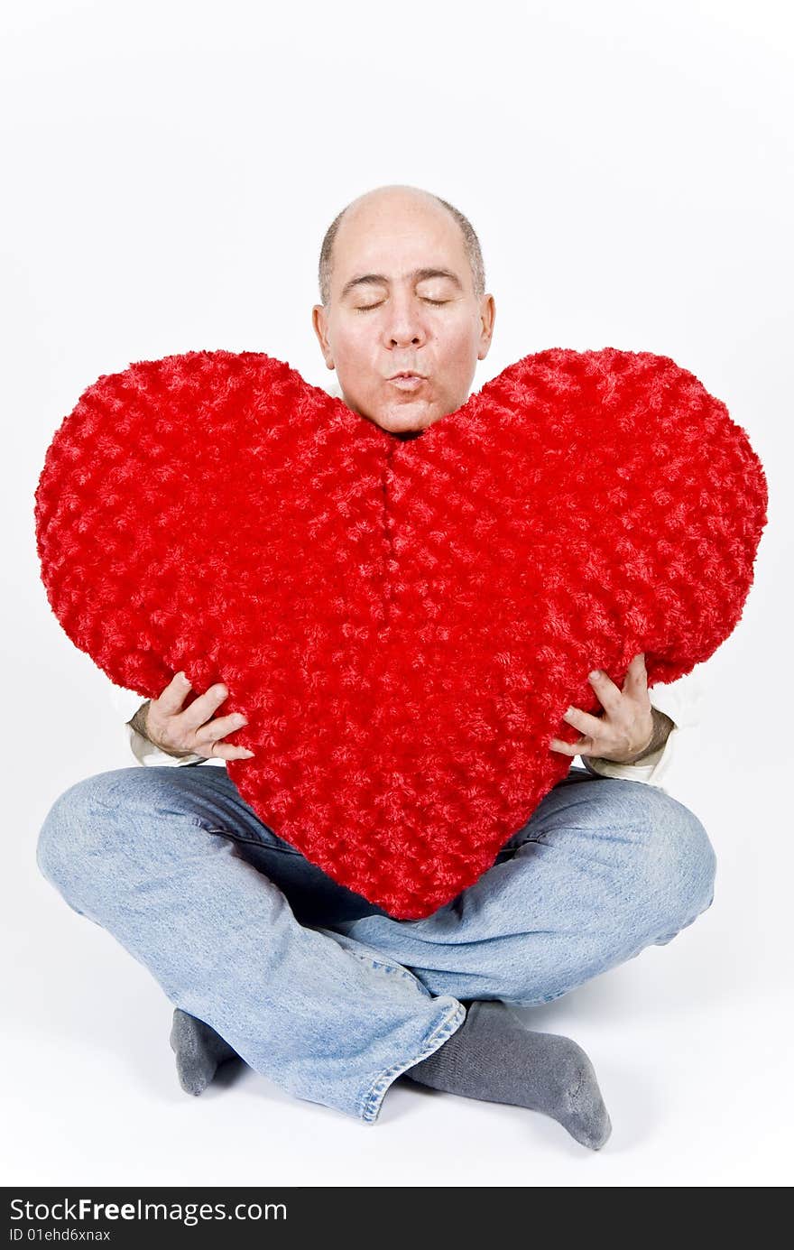 A handsome Latin man sitting holding a big red heart. A handsome Latin man sitting holding a big red heart.