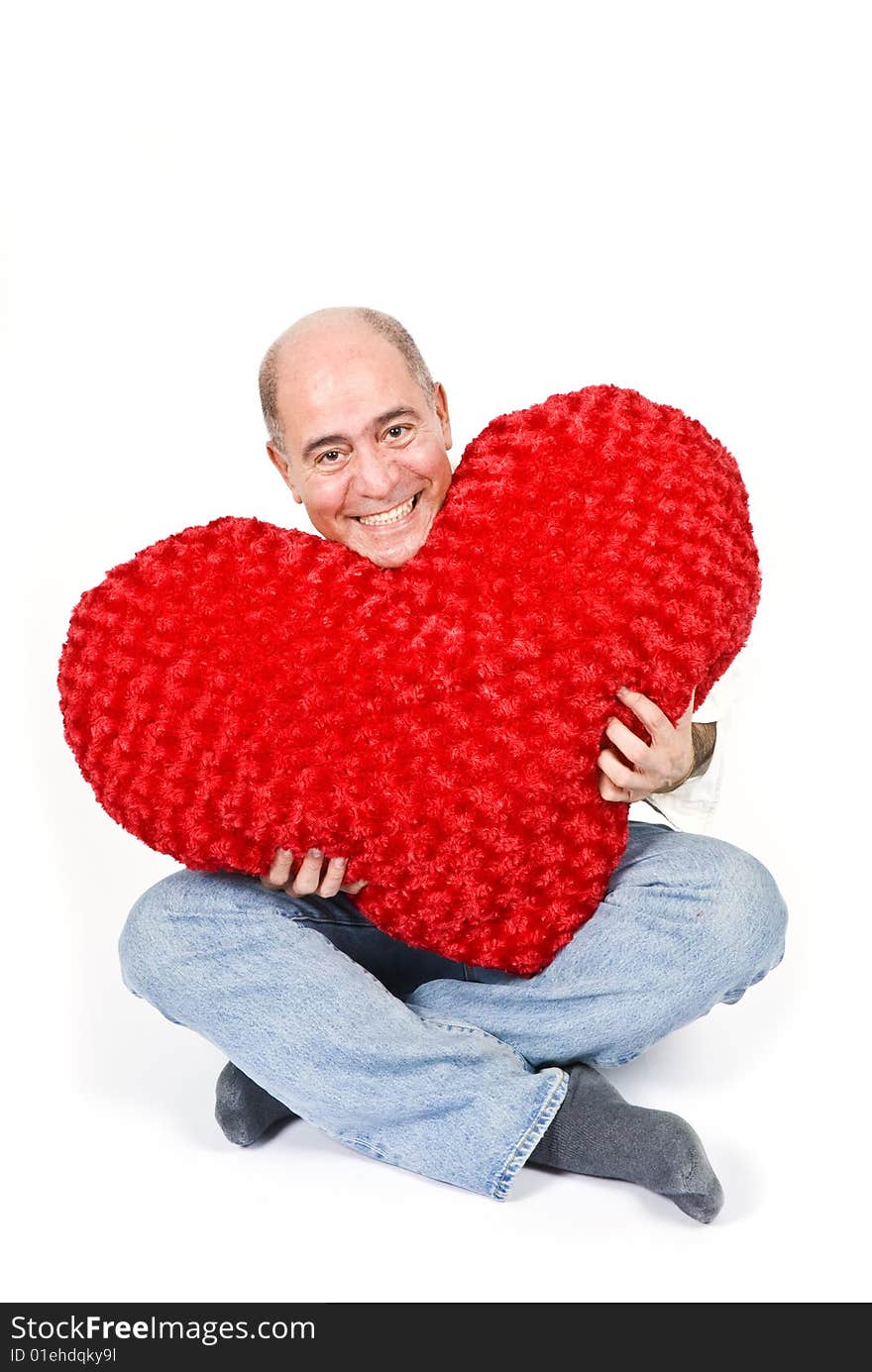 A handsome Latin man sitting holding a big red heart. A handsome Latin man sitting holding a big red heart.