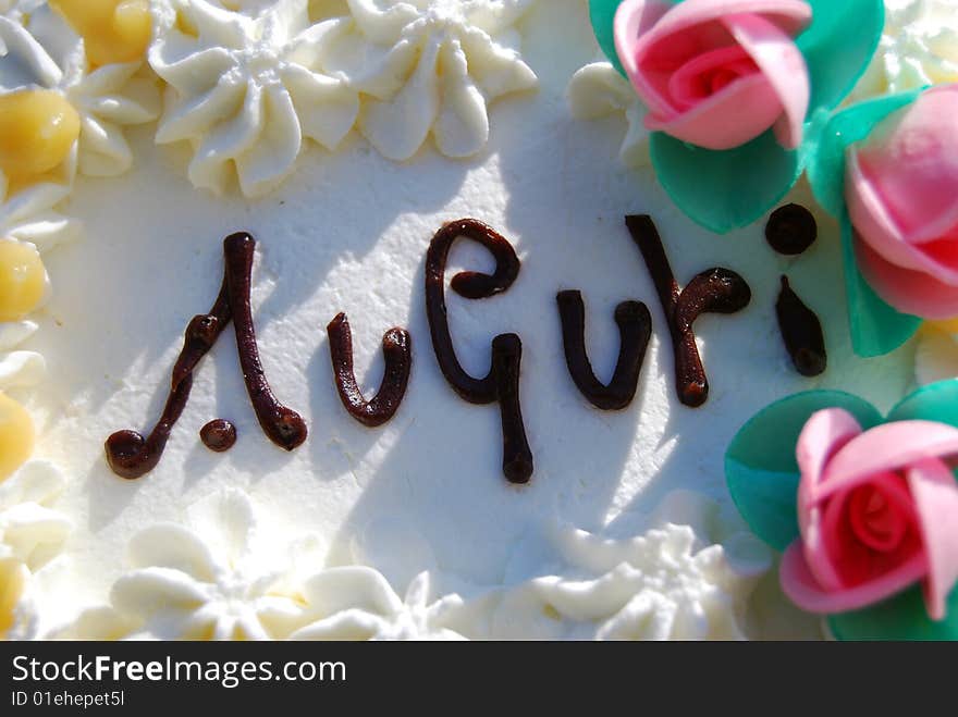 Birthday cake with auguri, cream and little roses, close up